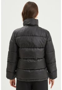 Giacca a vento nera con collo alto, cuciture orizzontali e finitura testurizzata. Presenta maniche lunghe e una vestibilità rilassata.