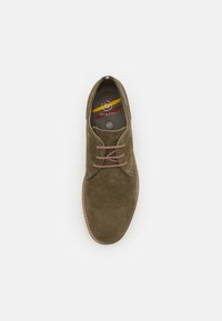Zapato verde de ante con cordones, de superficie texturizada, puntera redonda y suela marrón claro. En el interior, presenta una plantilla con marca y tamaño 42.