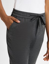 Zwart en wit gestreepte broek met een elastische tailleband, aantrekkoord, zijzakken en een getailleerd ontwerp. Zachte stof met een gematteerde afwerking.