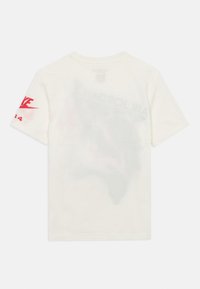 Λευκό βαμβακερό μπλουζάκι με κοντά μανίκια, που φέρει κόκκινο λογότυπο Nike και κείμενο «AIR JORDAN» σε συνδυασμένο γραφικό σχέδιο στην πλάτη.