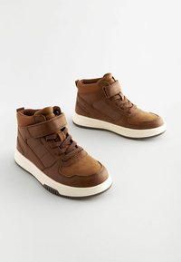 Bruine hoge sneakers van faux leer met een gestructureerd ontwerp, voorzien van een klittenbandsluiting, veters en een witte rubberen zool.