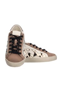 Zapatillas en tonos bronce y blanco roto con un patrón de manchas negras, que cuentan con cordones negros brillantes, textura suave y un diseño de puntera redonda.