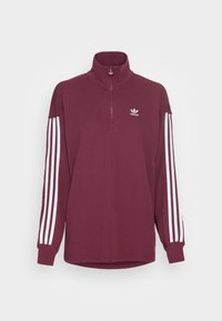 Sudadera burdeos con cuello alto y cremallera de cuarto. Acentos en blanco con tres rayas en las mangas y logo en blanco en el lado izquierdo del pecho. Textura suave.