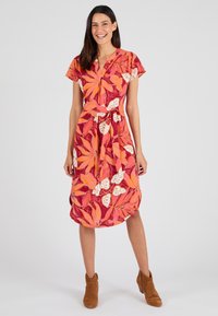 Robe fleurie avec un motif rouge et orange vif, des accents blancs, des manches courtes, une taille à nouer et un ourlet à mi-genoux.