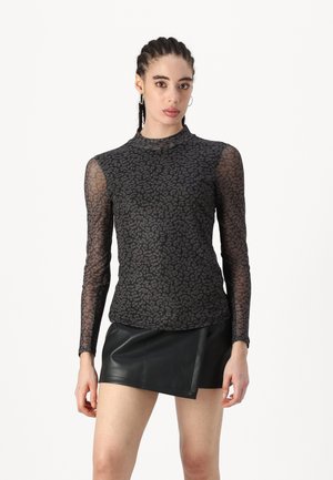 Zwarte lange mouwen top met een doorzichtige luipaardprint, hoge hals en aansluitende pasvorm, gecombineerd met een zwarte neplederen minirok.