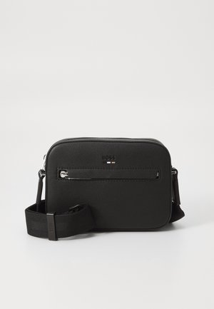 Sac bandoulière rectangulaire noir avec poche zippée à l'avant, surface texturée et sangle en tissu réglable sur fond blanc uni.