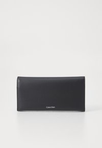 Čierna kožená peňaženka s elegantným, obdĺžnikovým dizajnom. Vyznačuje sa hladkým povrchom a diskrétnym logom Calvin Klein v dolnej časti.