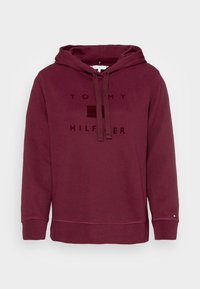 Vínová mikina s logem na přední straně, stahovací šňůrkou a žebrovanými manžetami. Hladký materiál s uvolněným střihem a rovním lemem.