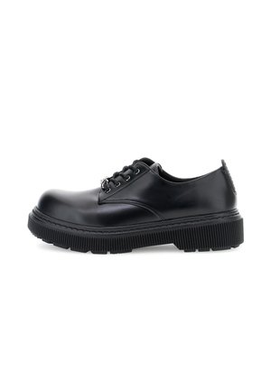 Scarpe stringate in pelle nera con suola spessa e scanalata, e occhielli in argento, mostrate in profilo laterale su sfondo bianco.