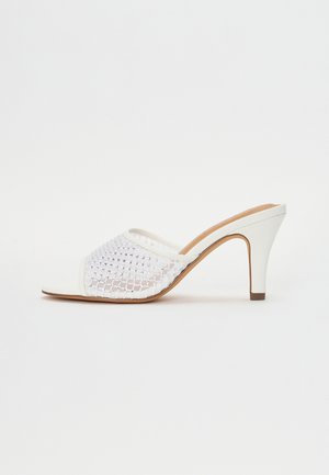 Bílé muly na vysokém podpatku s pleteným síťovaným svrškem se třpytivými akcenty, otevřenou špičkou a hladkou koženou podrážkou s zúženým podpatkem.