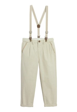 Beżowe spodnie sztruksowe z podwiniętymi mankietami i regulowanymi beżowymi szelkami przymocowanymi za pomocą brązowych skórzanych akcentów.
