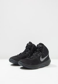 Czarne sportowe buty wysokie z siateczkowej cholewki, teksturowanym wzorem i szarym logo Nike. Oferują system sznurowania i gumową podeszwę.