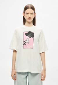 Valge puuvillane T-särk lahtise lõikega, millel on roosa graafiline kujutis liikuva figuuriga ja must pilv, ümara kaelusega ning lühikeste varrukatega.