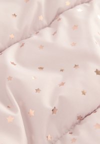 Couverture matelassée en tissu rose clair, ornée de motifs d'étoiles en or rose métallique, avec une texture douce et lisse.