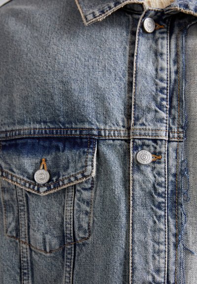 Denim jacket with light blue wash, visible stitching, two front pockets with silver buttons, and a classic shirt collar design.