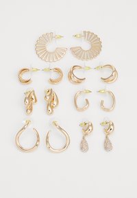 Ensemble de 12 boucles d'oreilles en ton or, comprenant des formes variées telles que des anneaux, des gouttes d'eau et des accents décoratifs, avec des fermoirs à pression transparents.