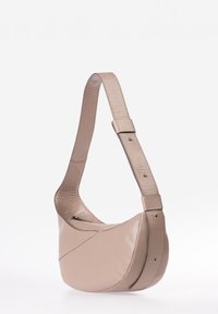 Borsa a spalla in morbida pelle beige con tracolla regolabile e ampia, chiusura con zip e design minimalista su sfondo bianco.