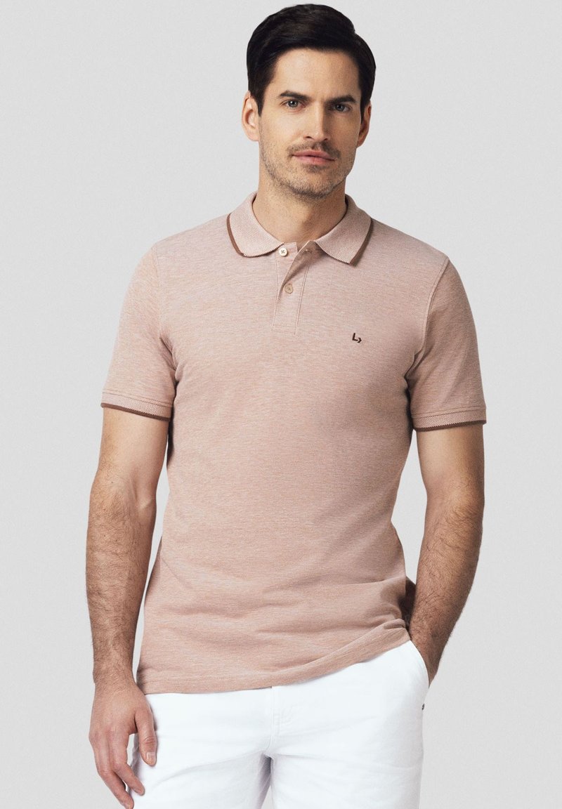 Koszulka polo w jasnoróżowym kolorze z prążkowanym kołnierzykiem i brązowym wykończeniem. Posiada logo na piersi oraz krótkie rękawy, wykonana z miękkiego, teksturowanego materiału.