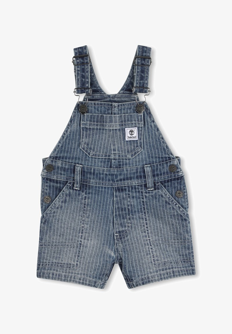 Salopette courte en jean bleu à fines rayures pour enfants, avec bretelles réglables et patch logo Timberland sur la poche avant.