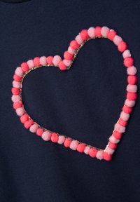 Marineblauer Stoff mit einem Herzdesign, umrandet von abwechselnden pinken und roten Pompons sowie glänzenden Paillettenakzenten.