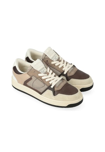 Una coppia di sneaker basse color beige, marrone e crema con chiusura a lacci e suole in gomma testurizzata su uno sfondo bianco.