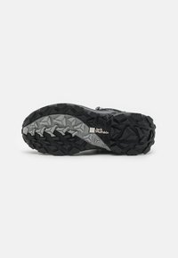 Suola di scarpa da trail nera e grigia con gomma testurizzata e motivi angolari, caratterizzata da un logo di marca prominente e un design del battistrada resistente.