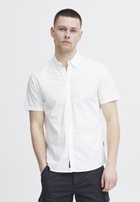 Witte kortekleurige overhemd met een gespreide kraag, zachte textuur en een rechte zoom. Gecombineerd met donkere cargoshorts.