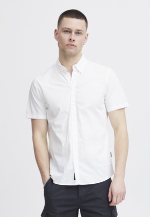 Chemise blanche à manches courtes avec un col écarté, texture douce et ourlet droit. Assortie à un short cargo sombre.