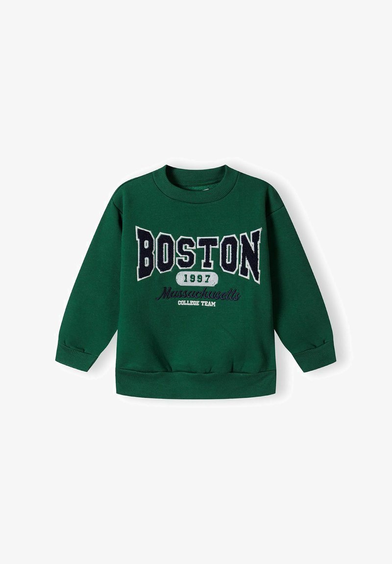 Roheline logošvetser, millel on ribitud varrukaotsad ja alumine äär. Esipinnal on suurte valgete ja tumesiniste tähtedega "BOSTON 1997" ja allpool tekst "Massachusetts College Team".