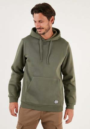 Olive green hooded sweatshirt made of soft fabric, featuring a kangaroo pocket and drawstring hood. Includes a small logo label at the hem.