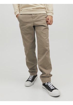 Khaki bomuldsbukser med en afslappet pasform, med lommer, og parret med sort og hvidt sneakers. Glat tekstur, enkelt design.