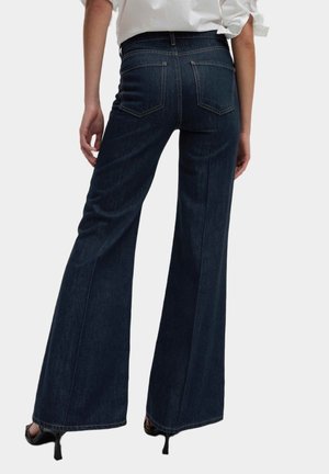 Granatowe dżinsy w fasonie dzwonów, wykonane z denimu, z wysokim stanem, tylnymi kieszeniami i gładkim wykończeniem bez widocznych ozdób.