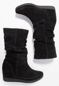 Bottes compensées en daim noir à design décontracté, avec tissu texturé, semelle en caoutchouc lisse et détails de coutures contrastées.