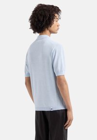 Polo shirt azzurro chiaro a maniche corte con un tessuto lavorato, con colletto e un piccolo etichetta del marchio sull'orlo. Design slim fit.