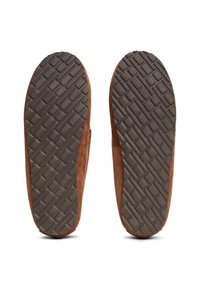 Ansicht der Außensohle eines Paares brauner Wildlederschlappen mit strukturierten Gummisohlen und Kreuzmuster.