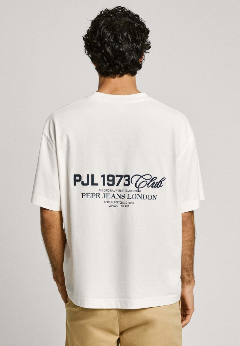 Fehér, kerek nyakú póló, hátán kék nyomtatott szöveggel, amely tartalmazza a "PJL 1973 Club" és a "Pepe Jeans London" feliratokat. Laza szabású, rövid ujjú.
