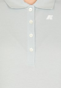 Polo shirt blu chiaro con un tessuto testurizzato, tre bottoni e un piccolo logo bianco sul lato sinistro del colletto.