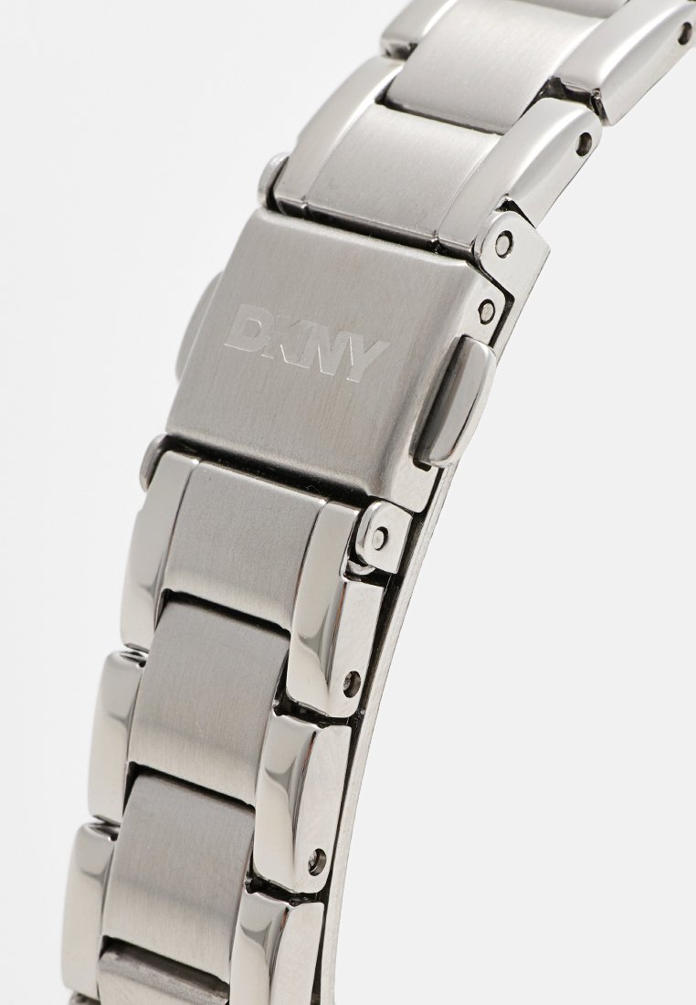 Edelstahlarmband mit polierten und gebürsteten Gliedern, ausgestattet mit einem DKNY-Logo auf der Schließe und einem eleganten, modernen Design.