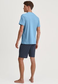 Lichtblauw katoenen T-shirt met korte mouwen, gecombineerd met marineblauwe shorts met een wit stippenpatroon. Minimalistisch ontwerp, casual pasvorm.