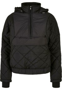 Svart quilted pullover-jakke med halv glidelås foran, hette og ribbede mansjetter. Har en kontrasterende panel over brystet. Myk tekstur.