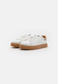 Zapatillas de cuero blanco con suela de goma, que cuentan con cordones en la parte frontal, punta redonda y un acento de beige texturizado en el talón.