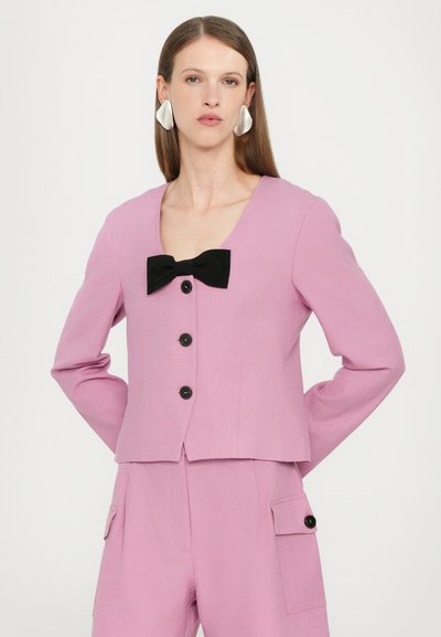 Pink blazer with a square neckline, black bow detail at the center, three black buttons, and long sleeves. Smooth texture.