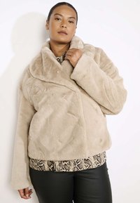 Beige faux fur jas met een brede kraag, lange mouwen en een licht cropped ontwerp. Gelaagde oppervlakte met een zachte afwerking.