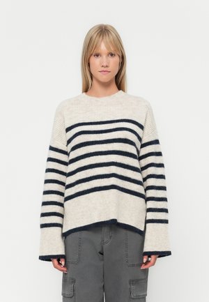 Pull en tricot rayé fait de fil beige clair et marine. Doté de manches longues, d'un col rond et d'une coupe décontractée avec une texture côtelée.