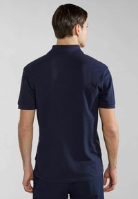 Laivasto sininen polo-paita, jossa on klassinen kaulus, lyhyet hihat ja teksturoitu pinta. Näkyvät saumat korostavat sivuja.