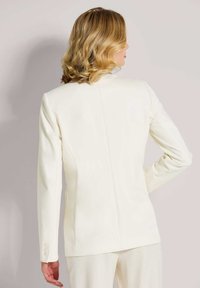 Witte op maat gemaakte blazer met lange mouwen, een gladde textuur en knoopaccenten op de manchetten. Heeft een getailleerd ontwerp en een enkele achternaad.