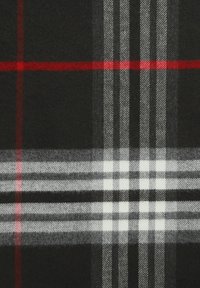 Czarny wełniany koc o wzorze w kratę z czerwonymi, białymi i szarymi paskami, łączący teksturę z elementami geometrycznymi.