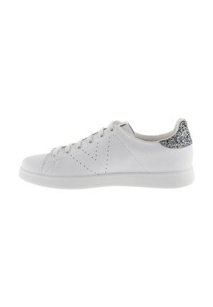 Sneaker bianca con lacci, design perforato sui lati e tab in plastica glitterata argento sul tallone, mostrata di profilo su uno sfondo bianco.