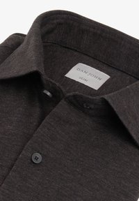 Slim fit -istutettu tummanruskea paita, jossa on teksturoitu kangas, nappikiinnitys ja kaulus, joka on taitettu. Etiketti kuuluu "DAN JOHN".