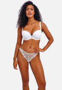 Soutien-gorge blanc rembourré avec finition en dentelle et string en dentelle assorti comportant des motifs floraux et des bretelles réglables. Texture lisse, design ajusté.